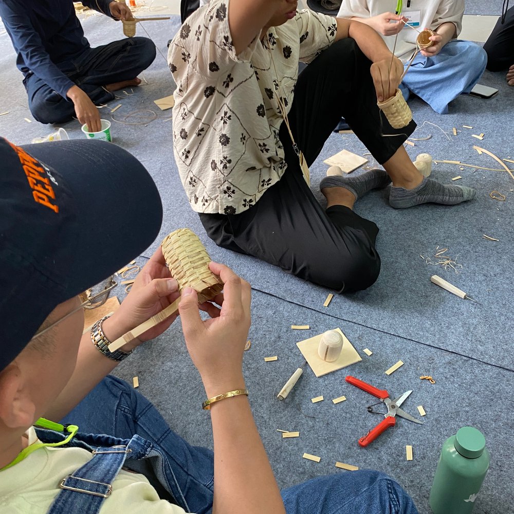 Hands weaving a bamboo basket in a craft workshop